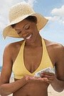 african american woman putting on sunscreen