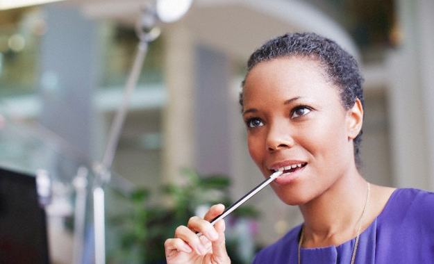 A woman biting the end of a pencil in her office