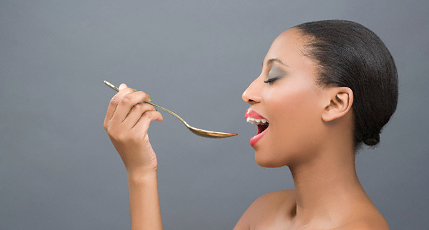 A woman holding a spoon up to her mouth