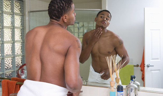 A man touching his skin and looking in the mirror
