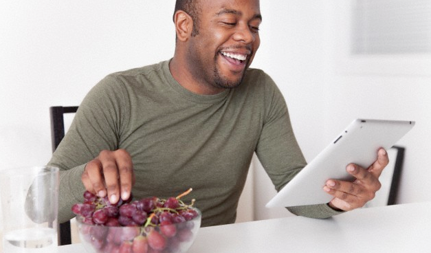 man eating grapes while holding an ipad