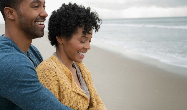 A couple embracing each other and smiling near a beach