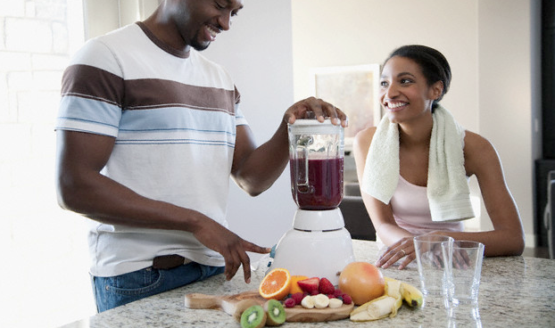 A man making smoothies in a blender while a woman looks at him