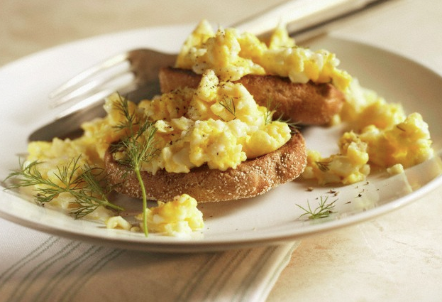 An English muffin and scrambled eggs on a plate
