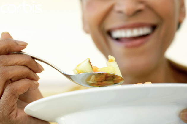 A smiling woman eating from a bowl