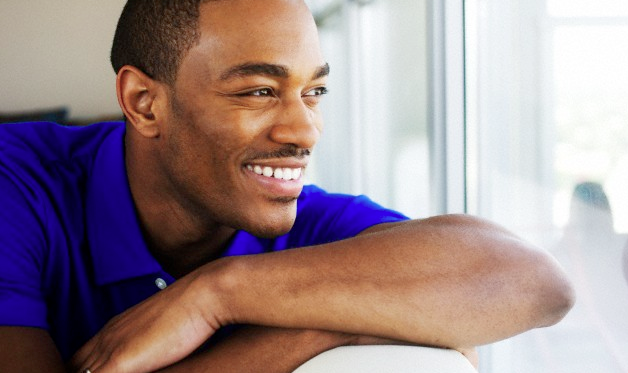 A man in a blue shirt smiling as he looks out a window