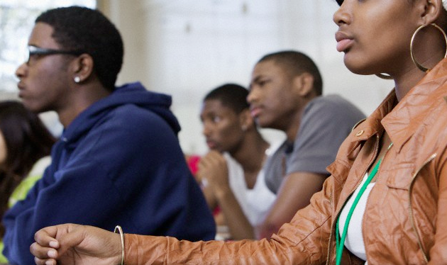 A teenage girl and several teen boys sitting in a classroom