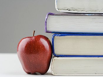 An apple sitting next to a stack of books