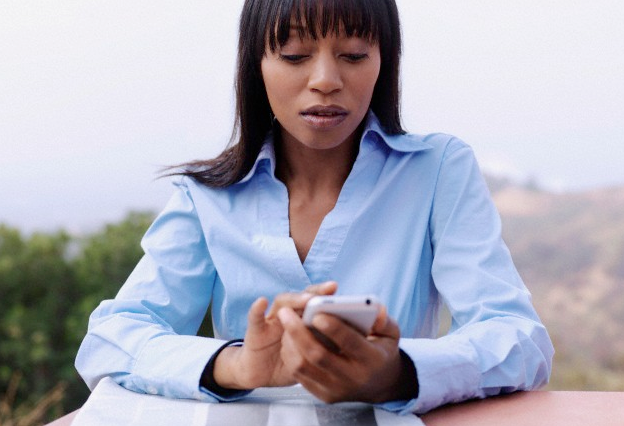 A woman in a blue shirt looking at her smartphone