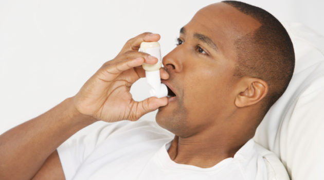Man using inhaler in hospital bed