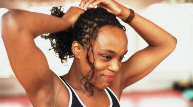 African American Black woman with braids putting hair in ponytail