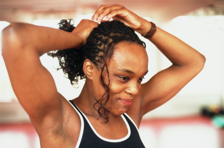 African American Black woman with braids putting hair in ponytail