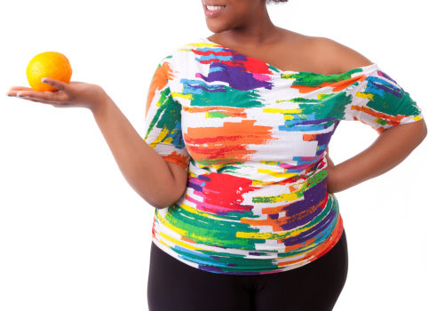 Overweight young black woman holding an orange