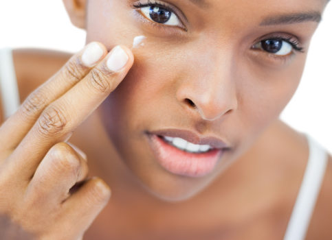 pretty african american woman putting moisturizer on her skin