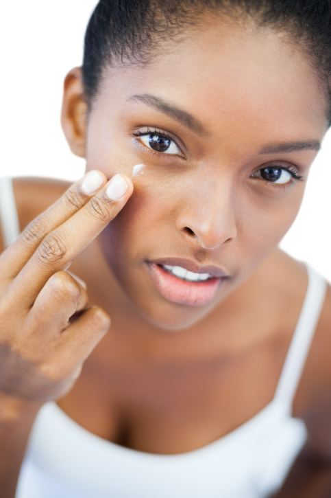 pretty african american woman putting moisturizer on her skin