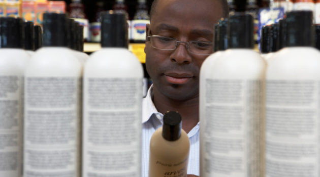 Man reading shampoo label in store, close-up