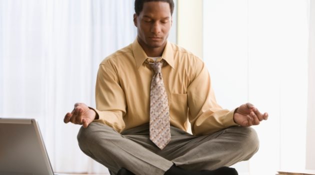 Black African American businessman meditating on desk