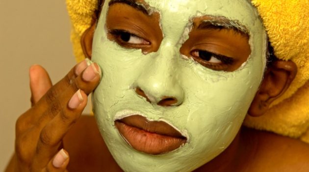 african american woman putting on facial mask