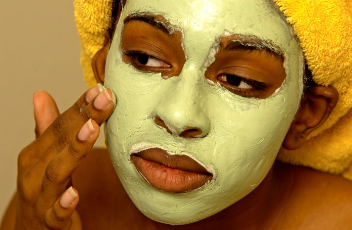 african american woman putting on facial mask
