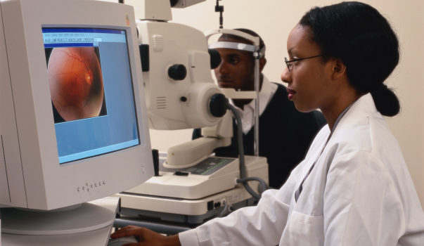 A female doctor examining a patient's eye on a computer monitor