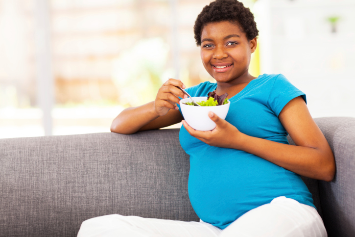 pregnant woman eating on couch