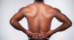 man holding lower back appearing to be in pain, backache
