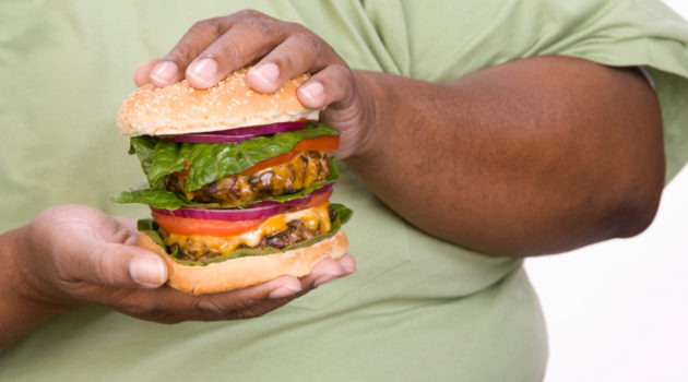 obese man holding double cheeseburger