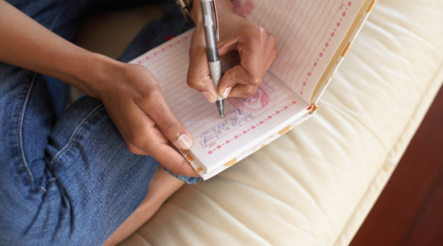 African American Black Woman's hands writing in journal