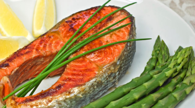 salmon steak dinner with asparagus and a lemon wedge