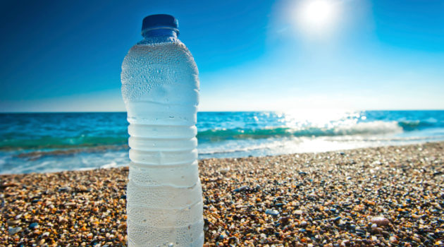 bottle of cold fresh water on the pebble beach