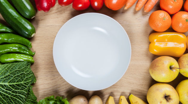 empty plate, surrounded by raw vegetables