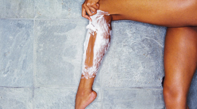 woman shaving legs with shaving cream and razor