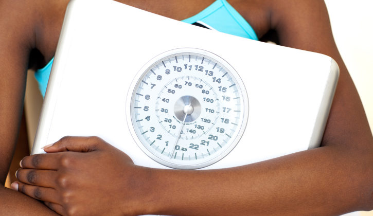 woman wearing gym clothes holding scale