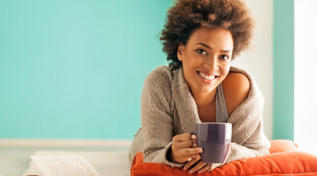 African American Black woman relaxing with cup of tea and book