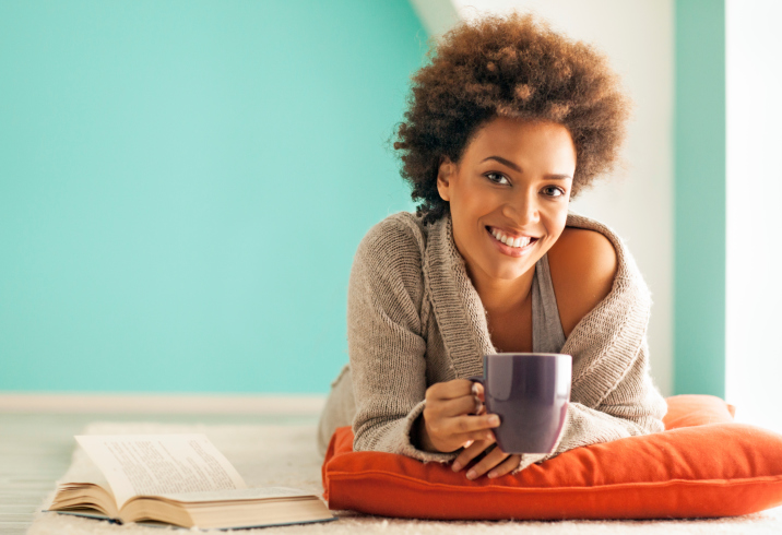 African American Black woman relaxing with cup of tea and book