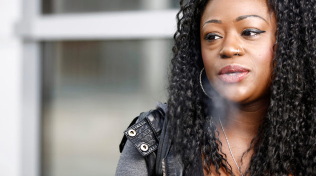 african american woman blowing out cigarette smoke