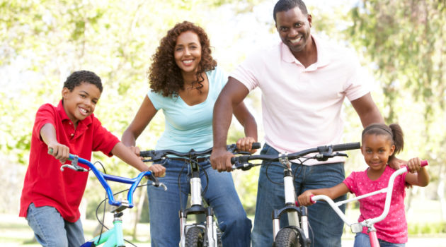 young family riding bikes in the park