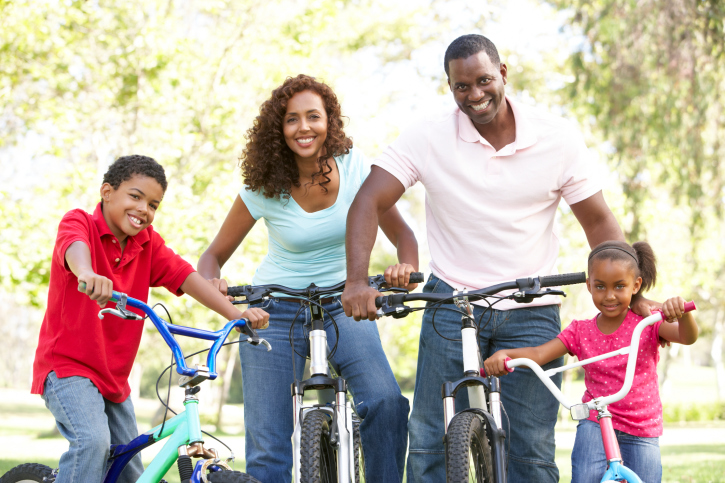 young family riding bikes in the park