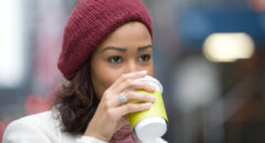African American woman walking drinking coffee