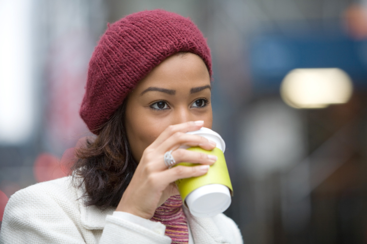 African American woman walking drinking coffee