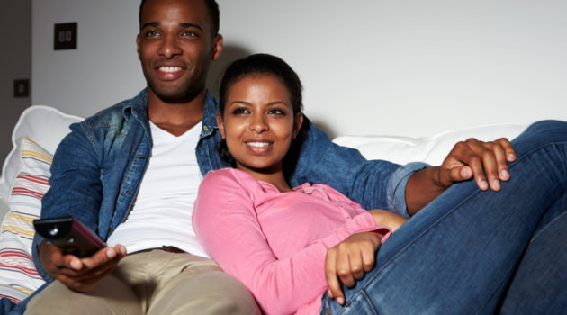 Couple Sitting On Sofa Watching TV Together