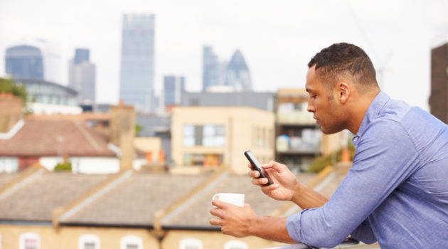 man looking at phone with coffee
