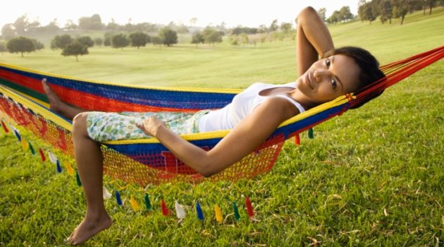 African American Black woman laying in hammock outside