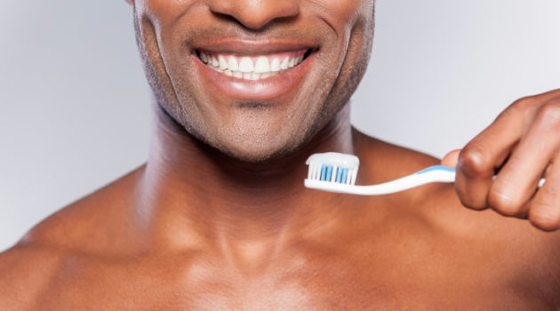 african american man smiling while holding a toothbrush