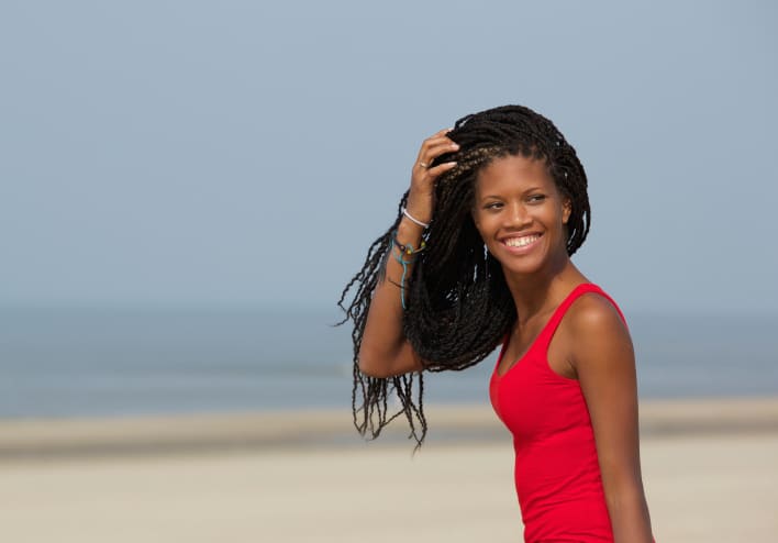 young woman with braids smiling on beach