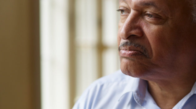 Older African American man looking out window