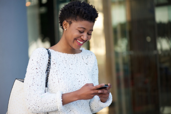 African American Black young woman walking and texting