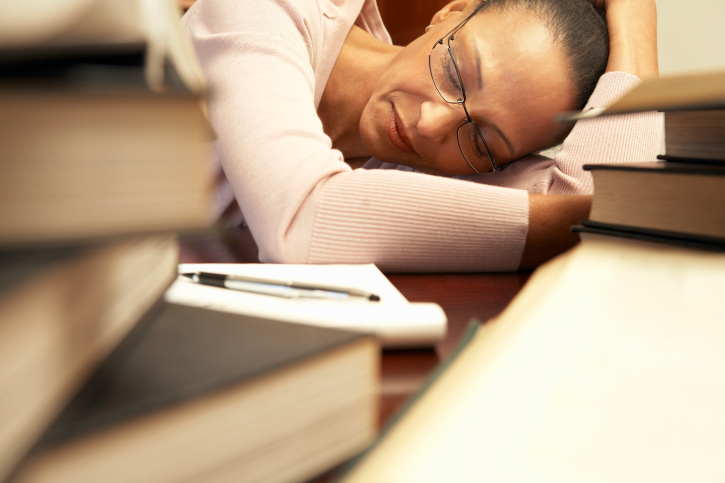 tired woman sleeping on a crowded desk