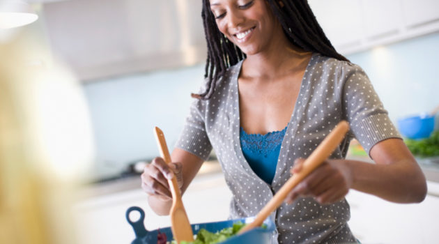 African American Black woman in kitchen mixing salad