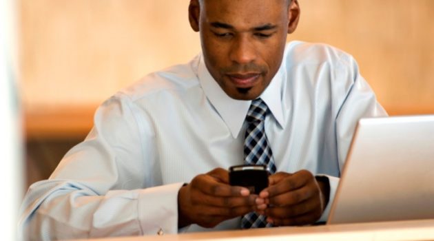 African American Black businessman texting and with laptop